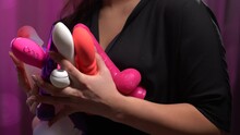mid section of woman holding different sex toys and vibrators