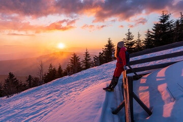 Wall Mural - Hiker with backpack relaxing on top of a mountain and enjoying valley view during sunrise. Lysa mount in Beskydy mountain in Czech Republic