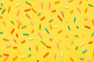 Wall Mural - flat lay of colorful sprinkles over yellow background, festive decoration for banner, poster, flyer, card, postcard, cover, brochure, designers