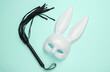 Sex shop toys. Rabbit mask with leather whip on blue background