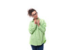 slender young brunette curly woman in glasses is dressed in a green shirt on a white background