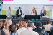 © Anton Gvozdikov - Businesspeople attending global presentation given by male and female professionals on stage in conference hall