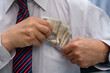 Przyjmować łapówkę, biznesmen chowa polskie banknoty do kieszeni