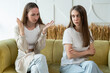 © Grustock - Unhappy two young women, a couple quarreling on the couch, a relationship in trouble. Two aggressive unsatisfied girls are sitting on the couch, screaming, fighting with each other in the bright