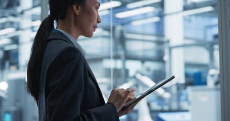 Aufkleber - Beautiful Asian Female Engineer Standing Next to a Window in Office, Using Tablet Computer at an Electronics Manufacture. Specialist Using an Online Software to Program Robots on Assembly Line