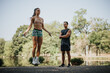 © qunica.com - Fit friends challenge themselves with an outdoor workout in the park. They stretch and warm up before jumping rope together, motivated and persistent. Positive results await.