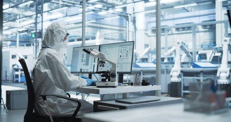 Fototapete - Modern Factory: Industrial Engineer Working on Desktop Computer in Clean Sterile Coveralls. Scientist Using a Microscope, Developing Advanced Solutions for High-Tech Medical Vaccine and Gene Research