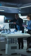 Fototapete - Vertical Screen: Industrial Robotics Specialists Working on a Mobile Robot, Using Tablet and Laptop. Black Male Engineer Discussing an Automated AI Robotic Delivery Assistant with His Young Team