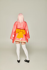 Wall Mural - back view of anime style woman in blonde wig and short pink kimono with white knee socks on grey