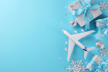 Concept Of A Christmas Vacation. Top View Flat Lay Of Gift Boxes, Yule Tree Ornaments, Miniature Plane, Snowflakes, Stars On Blue Background With Promo Zone