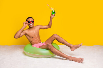 Sticker - Full length photo of attractive excited shirtless man sitting inflatable circle rising cocktail glass isolated yellow color background