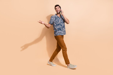 Canvas Print - Full length photo of young man talking people making a phone call looks for information empty space isolated on beige color background