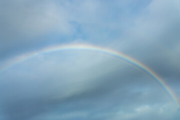 Real photo of a rainbow in the sky with clouds and blue sky