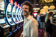 lucky young man smiling near slot machines in a casino