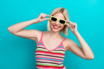 Sticker - Photo of attractive nice young hipster lady touching sunglasses ray ban posing model wear knit singlet isolated on cyan color background