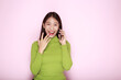 © Parichat - Portrait of a beautiful young woman in a light pink background, happy and smile, posting in stand position, Asian woman looks surprised while holding phone in hand