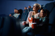 © Drazen - Happy senior woman and her granddaughter watching movie in theater.