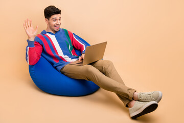 Poster - Full length photo of cheerful young worker waving palm greetings welcome to his colleagues online meeting isolated on beige color background