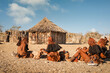 Group of Himba women in traditional attire sitting in front of their huts in a small village located near Opuwo, Kunene Region, Namibia. Himba is a traditional tribe in Africa.