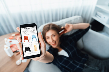 Young happy woman buy product by online shopping at home while ordering items from the internet with credit card online payment system protected by utmost cyber security from online store platform