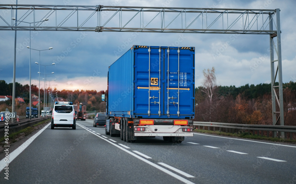 A cargo truck with a standard twenty-foot container on a motorway ...