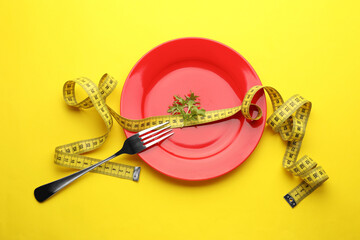 Canvas Print - Plate with arugula, measuring tape and fork on yellow background, top view. Diet concept