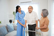 © offsuperphoto - nurse or caregiver helping senior man walking with a walker and senior woman support him at home