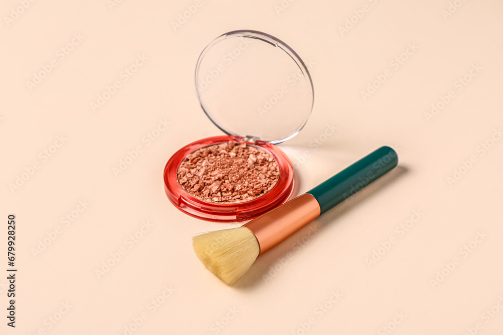 Makeup brush and highlighter on pink background