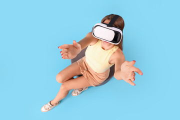 Wall Mural - Young woman using VR glasses on blue background, top view