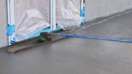 Canvas Print - An employee plasters wet concrete cement floor using trowel after concrete has just been poured