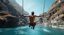 Man Swinging Between Blue Waters Of A Canyon