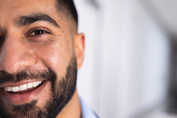 Half portrait of happy biracial male doctor in hospital corridor with copy space