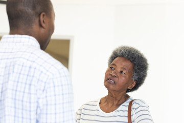 Wall Mural - African american male doctor talking with senior woman in hospital reception