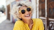 Head And Shoulders Portrait Of Laughing Senior Woman outdoors wearing sunglasses