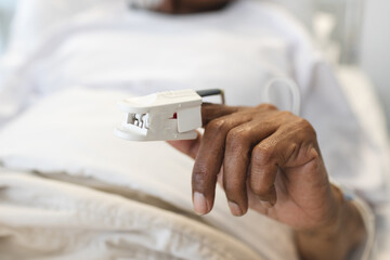 Wall Mural - Hand of african american senior female patient lying in bed in sunny hospital room