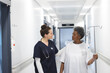 © wavebreak3 - Diverse female doctor talking with senior female patient with drip in hospital corridor