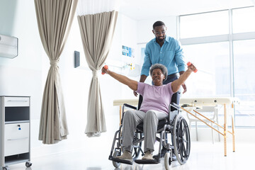 Wall Mural - African american senior woman exercising with weights and male doctor advising in hospital room