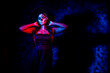 © Kaushik - A women with Halloween Makeup in blue red light giving out a horror look wearing black gown in black background