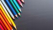 Pencils of different colors in a row on a black textured background