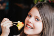girl with a canape. young girl sitting in a cafe with a canape stick in her hand, food concept