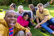 © Wavebreak Media - Portrait of happy diverse teenage friends taking selfie and sitting on grass in park