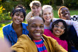 © Wavebreak Media - Portrait of happy diverse teenage friends taking selfie and sitting on grass in park