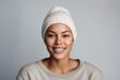 © CogniLens - Portrait of a tender woman in her 30s sporting a trendy beanie against a white background. AI Generation