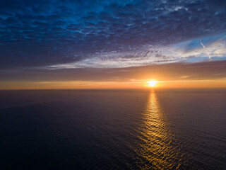 Wall Mural - A view from a drone flying over the sea early in the morning at sunrise, with the rising sun and a colorful sky