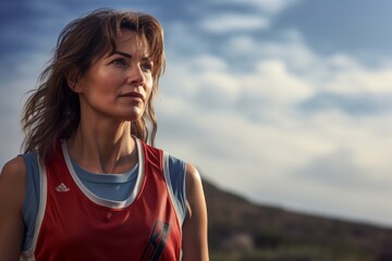 Wall Mural - Portrait of a satisfied woman in her 40s dressed in a high-performance basketball jersey against a quiet countryside landscape. AI Generation