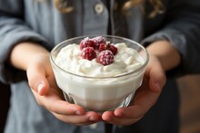 woman holding a bowl with yogurt and raspberries