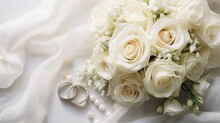  A Bouquet Of White Roses And Two Wedding Rings On A Bed Of White Fabric With Pearls And Pearls On The End Of The Bouquet And A Ring On The End Of The Bouquet.