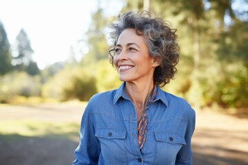 Wall Mural - Portrait of a tender woman in her 50s sporting a versatile denim shirt against a bright and cheerful park background. AI Generation