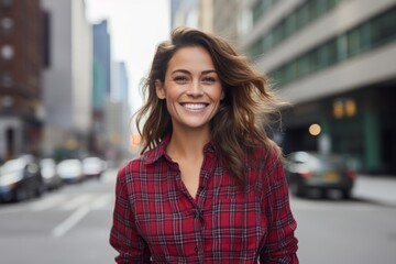 Wall Mural - Portrait of a cheerful woman in her 30s wearing a comfy flannel shirt against a bustling city street background. AI Generation