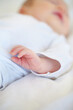© Tabitha Rose/peopleimages.com - Closeup, baby or new born with hand on bed for love, caring and support in home. Infant, hope and milestone for future, growth or child development with trust for bonding, protection and security
